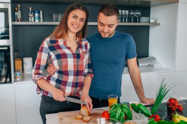 Genç çift akşam yemeği hazırlıyor. Kız kesme besindir. H adamdır