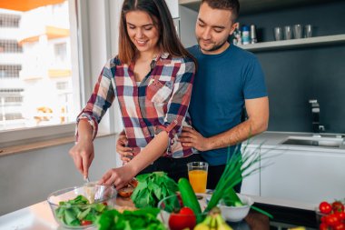 Genç çift akşam yemeği hazırlıyor. Kız kesme besindir. H adamdır