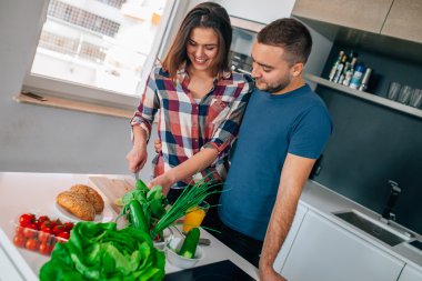 Genç çift akşam yemeği hazırlıyor. Kız kesme besindir. H adamdır
