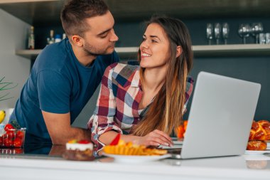 Genç kithcen içinde oturan ve dizüstü bilgisayar kullanarak çift. H olduklarını