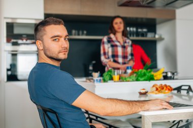 Genç çift mutfakta. Adam masanın oturan ve