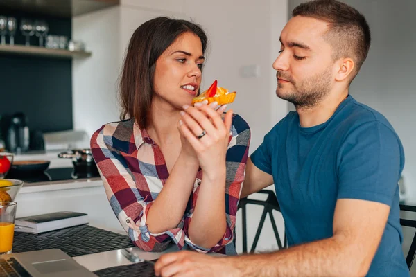 Pareja joven sentada en la cocina y degustando capcakes con fr — Foto de Stock