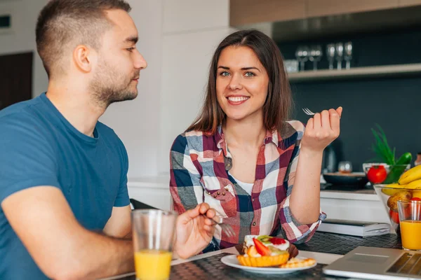 Pareja joven sentada en la cocina y degustando capcakes con fr — Foto de Stock