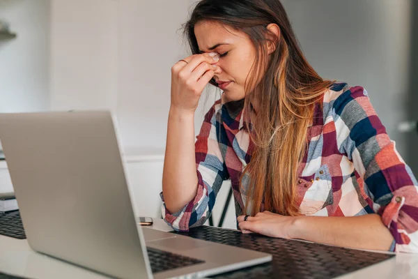 Ung flicka med laptop i köket. Hon har en fruktansvärd heada — Stockfoto