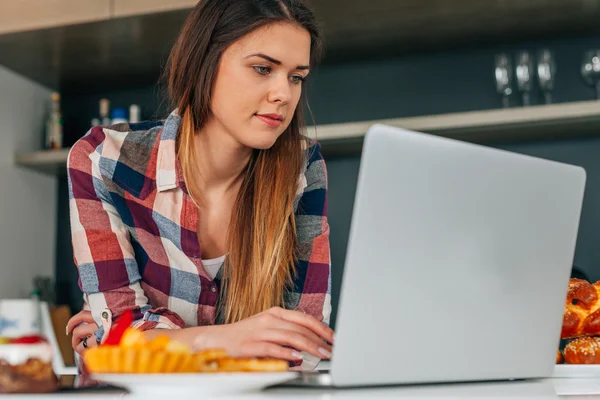 Joven mujer hermosa usando el ordenador portátil en el kithcen . — Foto de Stock