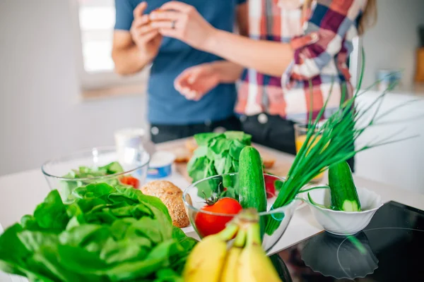 Jong koppel in de keuken. Op het eerste plan groenten en fr — Stockfoto