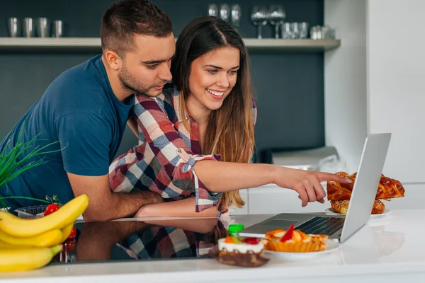 Pareja joven sentada en el kithcen y usando laptop. Chica es sh — Foto de Stock