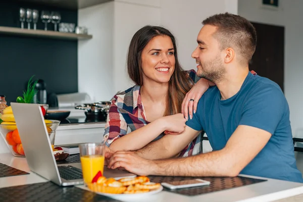 Kithcen içinde oturan ve dizüstü bilgisayar kullanarak genç Çift.