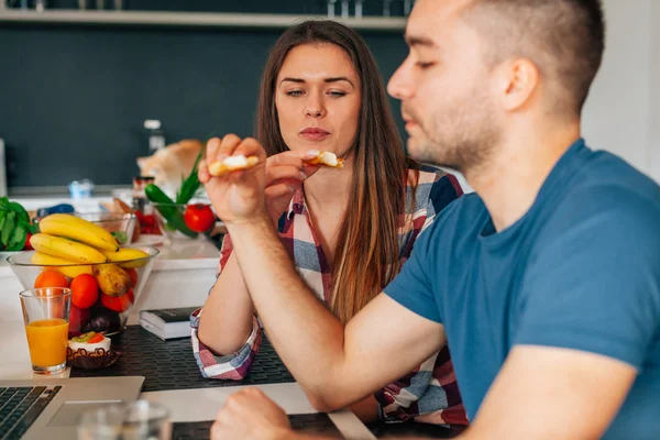 Jong (echt) paar zitten in de keuken en proeverij capcakes met fr — Stockfoto