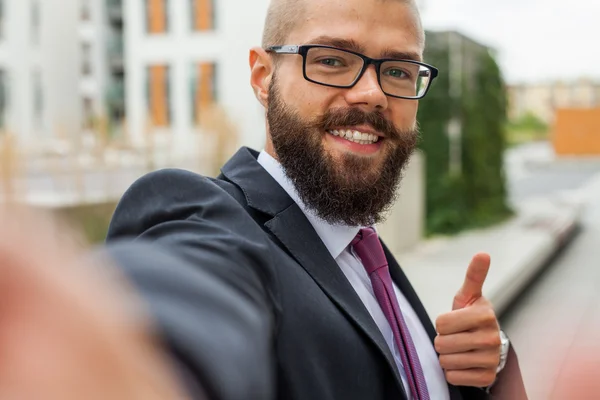 Young happy bearded businessman standing outside office building — Stock Photo, Image