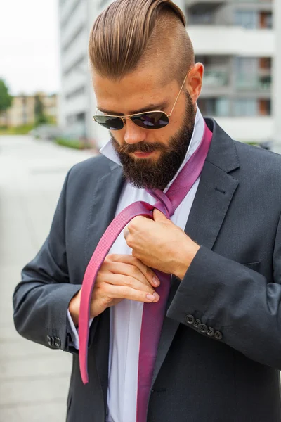 Joven empresario atractivo ajustando su corbata. Foto al aire libre . — Foto de Stock