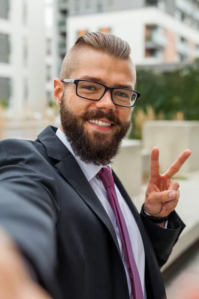 Young happy bearded businessman standing outside office building — Stock Photo, Image