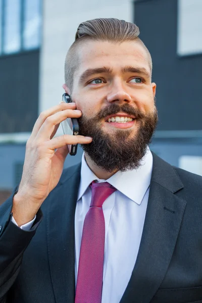 Young bearded businessman wearing eyeglasses using mobile phone — Stock Photo, Image