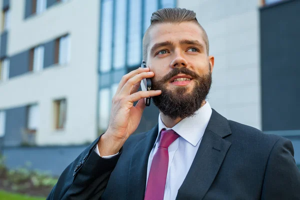 Joven hombre de negocios barbudo con anteojos usando teléfono móvil —  Fotos de Stock