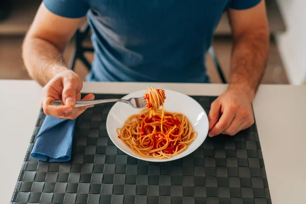 Молодой человек ест спагетти болоньезе. Закрыть . Лицензионные Стоковые Фото