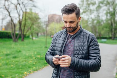 Parkta cep telefonu kullanan genç adam.. 