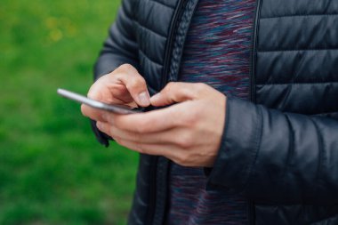 Parkta cep telefonu kullanan adam. Yakın çekim. 