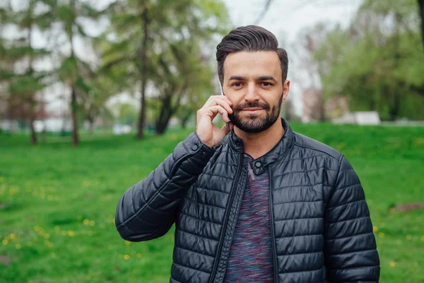 Ung man pratar i telefon i parken. — Stockfoto