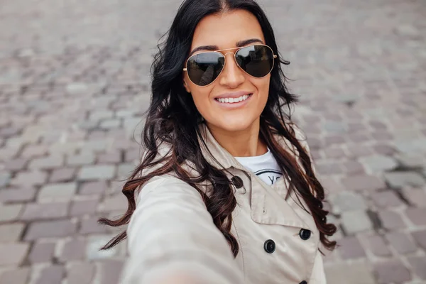 Una joven con gafas de sol se está tomando selfie. Fondo urbano . — Foto de Stock