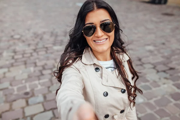 Una joven con gafas de sol se está tomando selfie. Fondo urbano . — Foto de Stock