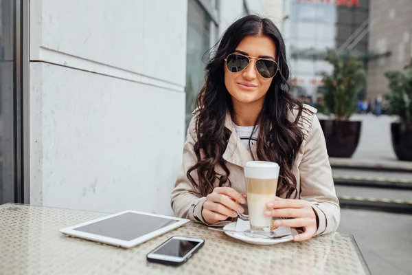 Frau sitzt mit Kaffee, Tablet-PC und Handy vor dem Café — Stockfoto