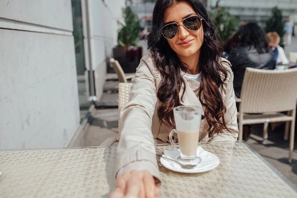 Mädchen sitzt außerhalb des Cafés und hält ihre junge Hand. — Stockfoto