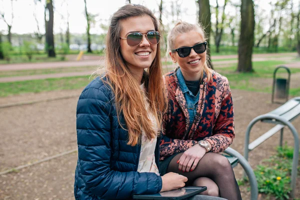 Две девушки сидят на беке в парке . — стоковое фото