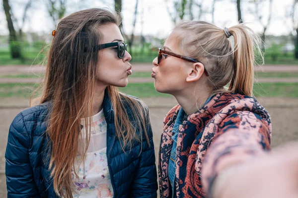 2 つの女の子が公園で撮影 selfie ベックの上に座って. — ストック写真