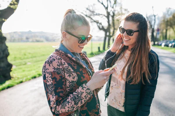 Dvě dívky, procházky v parku a poslechu hudby. — Stock fotografie