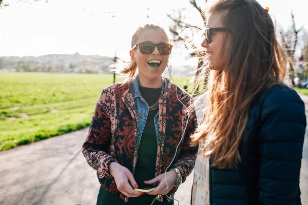 Deux filles marchant dans le parc et écoutant de la musique . — Photo