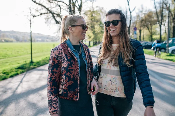 Zwei Mädchen, die im Park spazieren und Musik hören. — Stockfoto