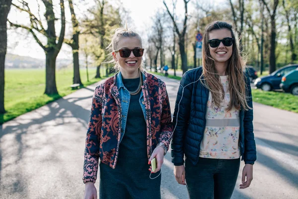 Zwei Mädchen, die im Park spazieren und Musik hören. — Stockfoto