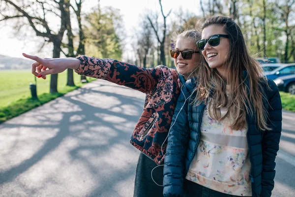 2 つの女の子が公園で音楽を聴きます。一人の女の子は、som を見せています。 — ストック写真