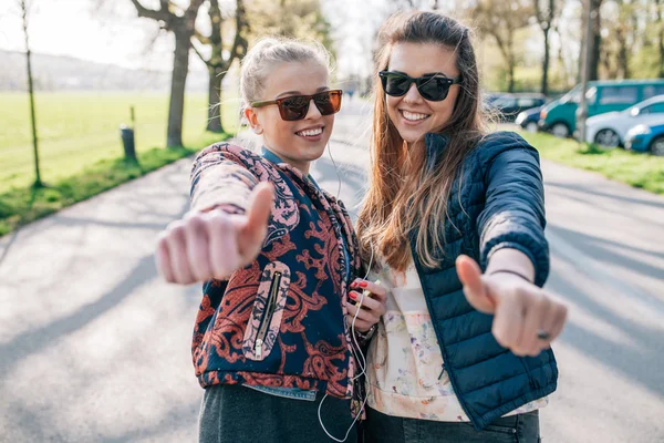 Zwei Mädchen hören Musik im Park. Positive Emotionen. — Stockfoto