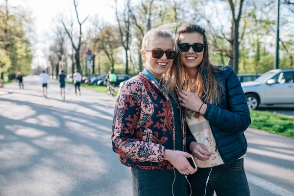 Zwei Mädchen, die im Park spazieren und Musik hören. — Stockfoto