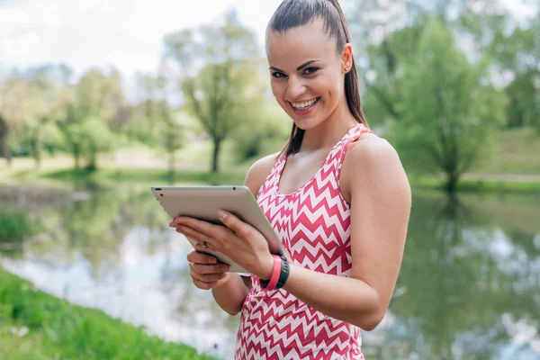 Dziewczyna jest za pomocą komputera typu tablet. Ona ma przerwę w treningu. — Zdjęcie stockowe