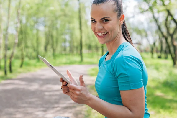Girl is using tablet pc. She has a break in workout. Close up. — Stock Photo, Image