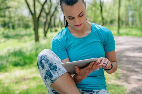 女孩使用 tablet pc。她在锻炼有休息。关闭. — 图库照片