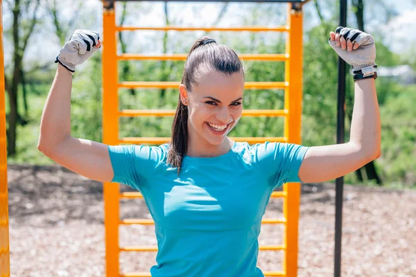 Girl is pulling up on the sport equipment in the park. — Stock Photo, Image