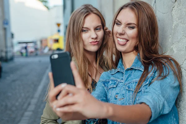 Twee jonge meisje nemen selfie op straat. — Stockfoto