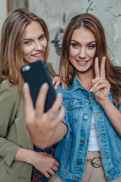 Dvě mladé dívky brát selfie na ulici. — Stock fotografie
