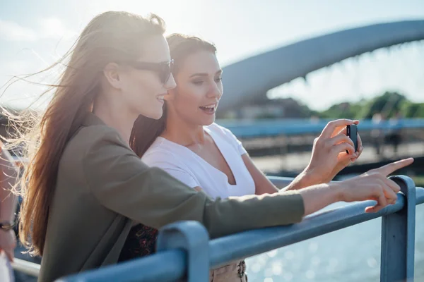 Two girls taking picture of the cityscape. River in the backgrou — Stock Photo, Image