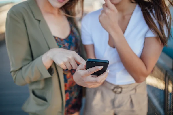 Zwei junge Mädchen mit Mobiltelefon. Sie befinden sich auf der Brücke. schließen — Stockfoto