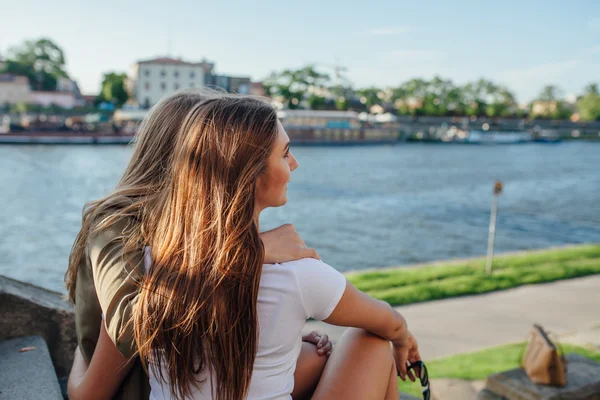 Two young girls sitting on the stairs next to the river and hugg — Stock Photo, Image