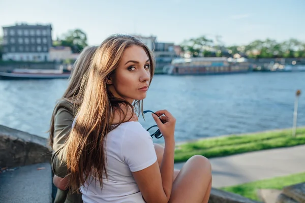 Dos chicas sentadas en las escaleras junto al río y abrazadas — Foto de Stock