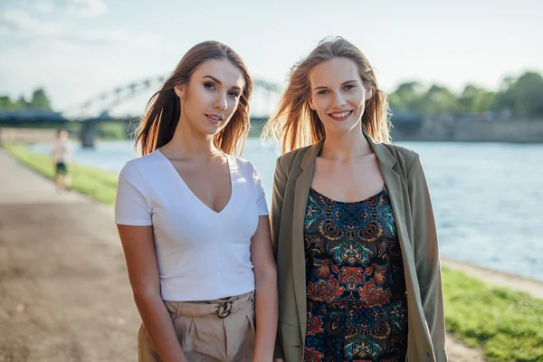 Two happy young girls standing next to the river. — Stock Photo, Image