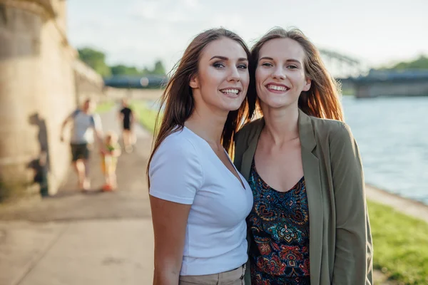 Two happy young girls standing next to the river. — Stock Photo, Image