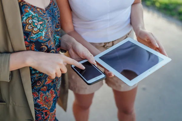 Två unga flickor står bredvid floden och med hjälp av tablet pc. — Stockfoto