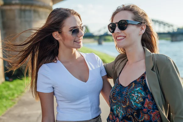 Zwei glückliche junge Mädchen, die am Fluss stehen und reden. — Stockfoto