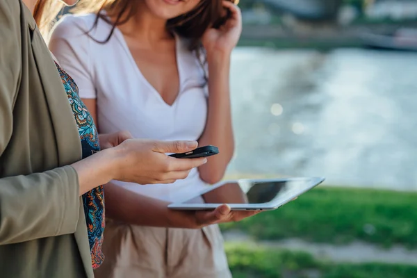 Zwei junge Mädchen, die am Fluss stehen und Tablet-PC benutzen. — Stockfoto